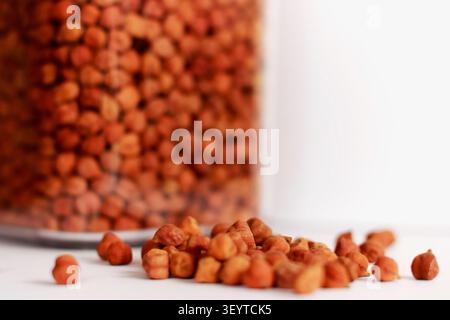 Raw Brown Chickpeas with Glass Storage Jar on White Background. Healthy Organic Legumes Close-Up Stock Photo