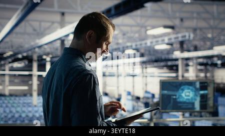 Smiling data center technician uses a tablet to review server infrastructure, diagnostics and AI technology in a data center. Stock Photo