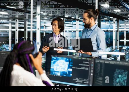 Data center colleagues collaborate on coding and AI automation scripts while reviewing server infrastructure together. Stock Photo