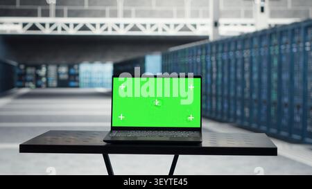 IT specialist uses green screen laptop in a data center to inspect hardware and maintain system stability. Stock Photo