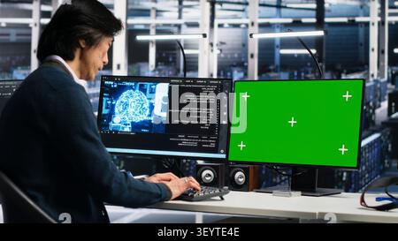 Programmer uses green screen PC in a server room to monitor AI diagnostics and neural network performance. Stock Photo