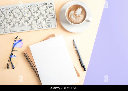 Minimalist workspace with keyboard, notebook, coffee, pen and eyeglasses on a pastel desk. Top view office composition with copy space, flat lay. Stock Photo