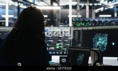 Data center technician arriving in office, working with AI visualization insights on computer to improve system health. Stock Photo