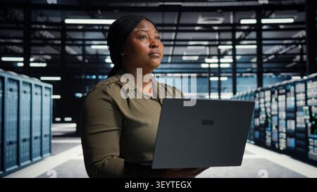 Technical specialist working with notebook computer in advanced technology server facility, integrating new technologies and systems. Stock Photo