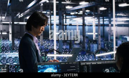 Team leader supervising technicians in server room working with AI to review infrastructure diagnostics. Stock Photo