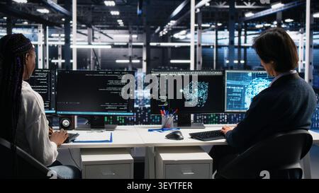 Server room system administrators working with machine learning models on computer to review data sets. Stock Photo