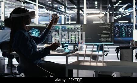 Administrator wears a headset in a server farm, using artificial intelligence troubleshooting to assist users. Stock Photo