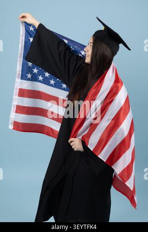 Proud graduate student holding a national flag celebrating degree Stock Photo