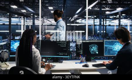 Server room manager checking work done by admins working with deep learning to review data sets. Stock Photo