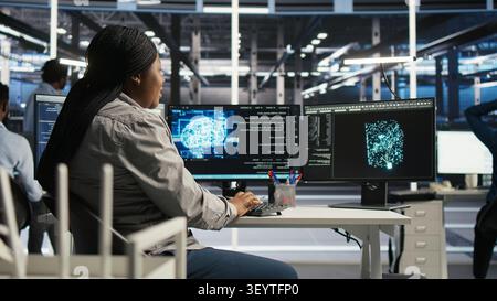 Server facility computing specialist applying AI ML models to set up hardware. IT specialist working with AI programming languages on workstation in server environment, optimizing system. Stock Photo