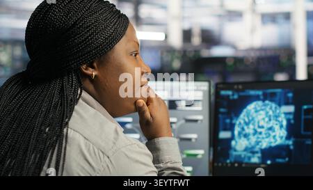 Server facility computing specialist applying AI ML models to set up hardware. IT specialist working with AI programming languages on workstation in server environment, optimizing system. Stock Photo