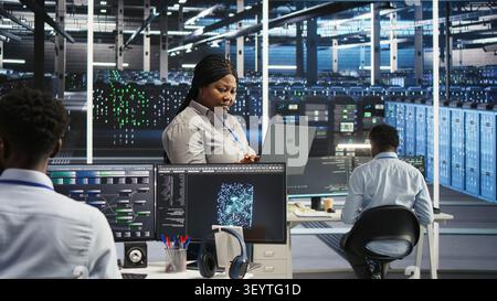 High tech server room system admin working with notebook to do visual programming. Stock Photo
