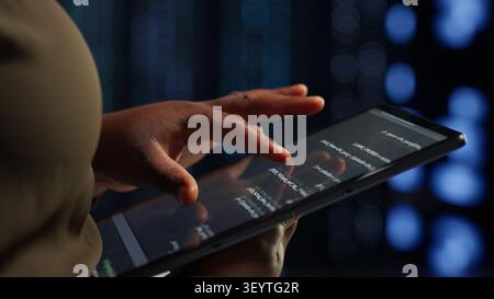 Data center administrator uses a tablet to roll out new server architecture, supporting reliable infrastructure operations. Stock Photo