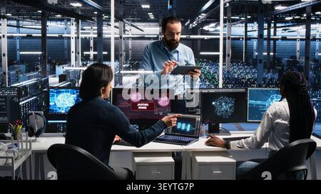 System administrators in server room struggle with computer bugs while working with AI. Stock Photo