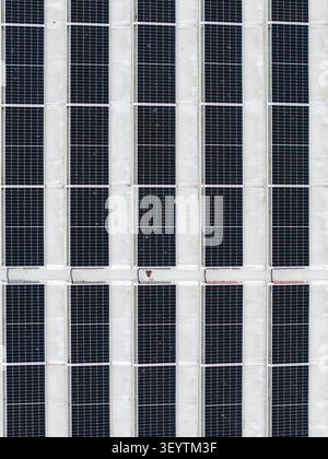 Aerial view of a large solar panel array installed on a flat industrial roof, showing clean geometric patterns and modern renewable energy infrastruct Stock Photo