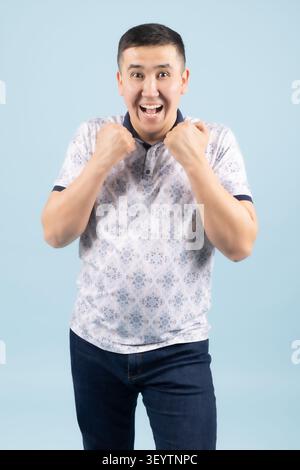 Excited young man holding hands near mouth looking surprised open Stock Photo