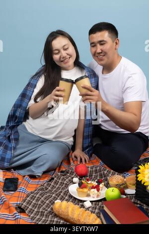 Happy young couple having an indoor picnic and toasting drinks Stock Photo