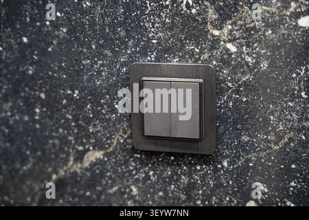 Modern switch on a textured marble wall in a luxury interior setting. Sophisticated design detail for contemporary residential and commercial spaces. Stock Photo