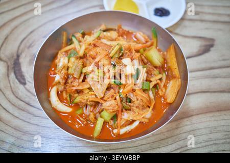 Authentic Korean mixed spicy noodles with vegetables and seafood in a metal bowl on a wooden table. A classic local regional dining experience.bibim, Stock Photo