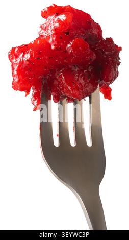 red ambarella chutney on metal fork isolated white background, sweet and spicy chunky fruit preserve with dark seeds, side view in macro close-up view Stock Photo