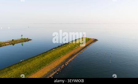 Aerial view of the harbor entrance with a red lighthouse on a grassy breakwater and a green lighthouse on the opposite pier in Stavoren, Friesland, Ne Stock Photo