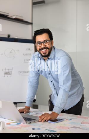 Portrait of smiling businessman reviewing charts at office desk Stock Photo