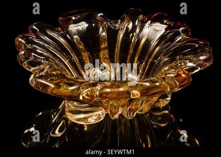 Vase of orange glass on a black background. At the bottom of the image is a reflection of the vase. Stock Photo