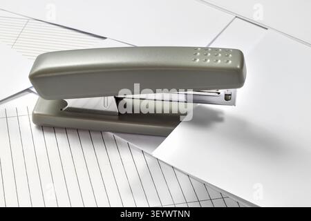 Stapler on a background of paper and letterhead. Close-up of stationery. Stock Photo