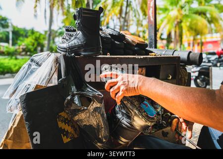 A close up shot of an Asian shoemaker's hand working on a black combat boot using pliers. Stock Photo