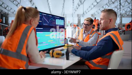 Diverse Team Of Technicians Uses Computers Controlling Robotic Car Production. Stock Photo