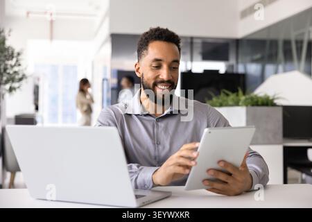 Professional man multitasking with tablet and laptop Stock Photo