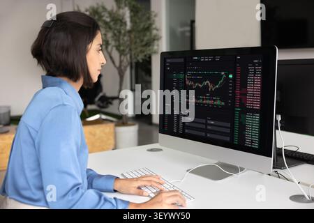 Financial analyst looking at trading dashboard on monitor Stock Photo