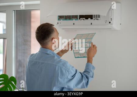 Man changing air conditioner filter, dirty mesh causing respiratory disease and poor ac performance. Stock Photo