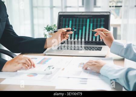 Business colleagues discussing laptop dashboard and financial charts during office meeting, representing data analysis, sales performance, teamwork an Stock Photo