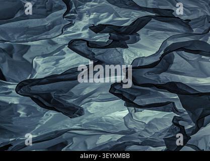 Close-up of crumpled translucent paper in cold blue-grey lighting. Textured background with a steel tint, deep shadows and dark folds in material. Stock Photo