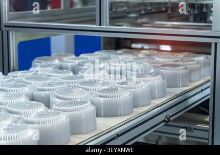 Stack of polypropylene food containers on conveyor belt of automatic plastic injection molding machine,automated technology concept Stock Photo