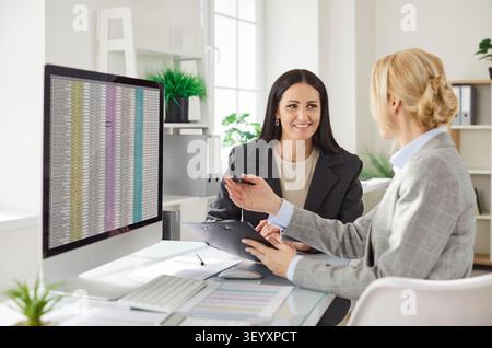 Two female financial accountants discussing financial data and analyzing spreadsheet in office. Stock Photo