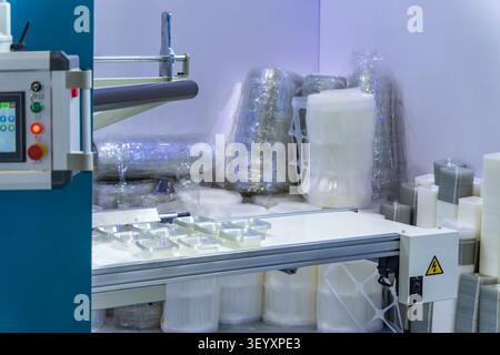 Stack of polypropylene food containers on conveyor belt of automatic plastic injection molding machine,automated technology concept Stock Photo
