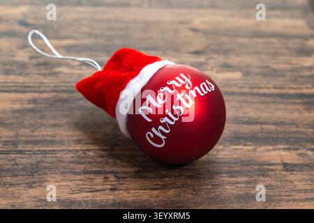 Red Christmas ball with words Merry Christmas on wooden background Stock Photo