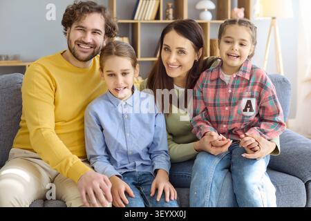 Happy family portrait of parents with two daughters smiling together at home Stock Photo