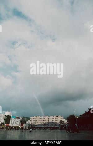 Rainbow arching over urban plaza in Hyderabad, India — modern buildings, cloudy sky, and Stock Photo