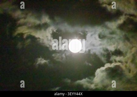 Full Moon Behind Dramatic Clouds At Night With Moody Moonlight And Eerie Sky Atmosphere Stock Photo
