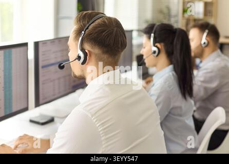 Call center operators with headsets working at computers in a modern office Stock Photo