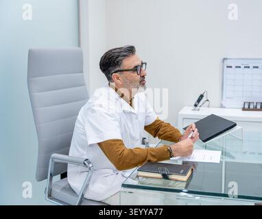 Doctor sitting at desk in clinic, consulting a patient Stock Photo