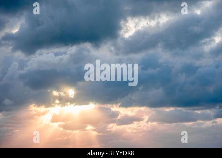 Dramatic sky with clouds and sunlight breaking through at sunset. Stock Photo