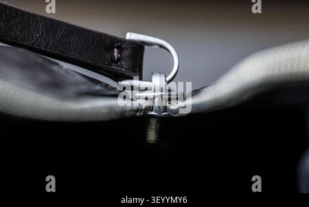 Close-up of a silver zipper slider with leather pull tab on a dark bag, shallow depth of field Stock Photo