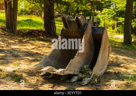 Excavator bucket resting on ground at construction site Stock Photo