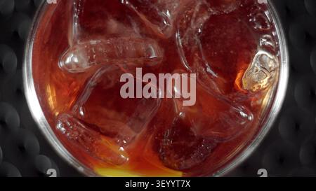 Cold refreshing dark beverage with ice cubes and lemon slice in a glass, top view, bubbles creating a refreshing texture Stock Photo