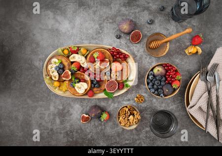Breakfast spread featuring pancakes, berries, figs and honey arranged on a rustic tabletop Stock Photo