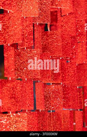 An abstract art installation featuring suspended translucent red panels with textured surface Stock Photo